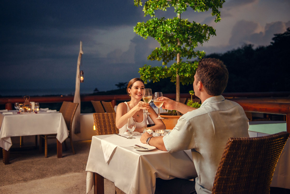 A couple dining on the Raixes terrace at dusk